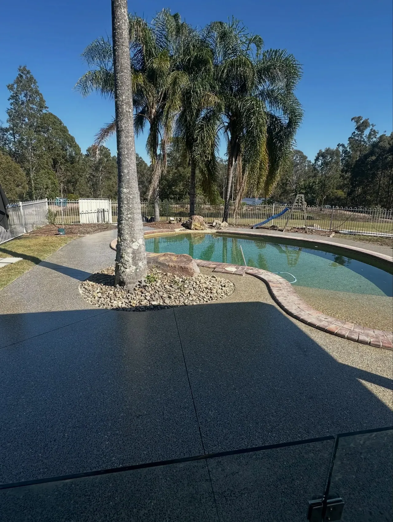 A completed honed concrete outdoor area beside a swimming pool